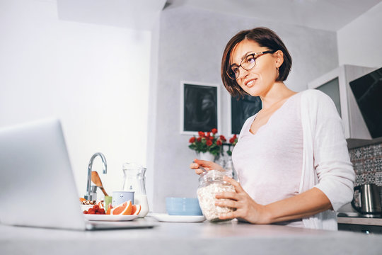 Woman prepare breakfast and watch a news in laptop