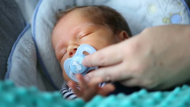 Mother give her newborn child dummy while sleeping
