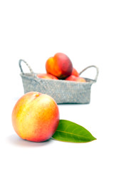 Ripe fresh nectarines in the wicker basket isolated on a white background