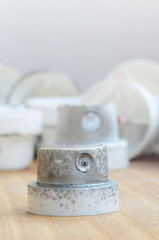Several plastic nozzles from a paint sprayer that lie on a wooden surface against a gray wall background. The caps are smeared in chrome paint. The concept of street art and graffiti © mehaniq41