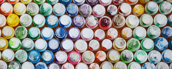 A pattern from a many nozzles from a paint sprayer for drawing graffiti, smeared into different colors. The plastic caps are arranged in many rows forming the color of the rainbow