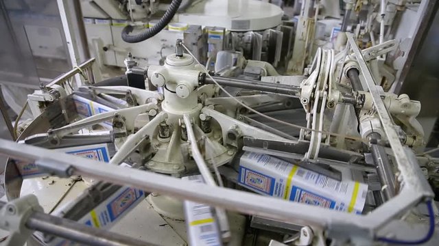 Filling empty boxes with flour at a flour mill. The conveyor for packing flour in bags. Packing flour at the factory mill. Production line for packaging. Manufacture of food products.