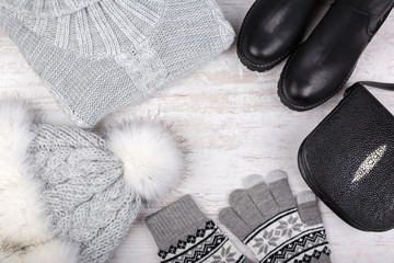 A set of fashionable winter women's clothing. Wool sweater, shoes, handbag, fur hat and gloves on white background.