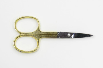 Dettaglio di un paio di piccole forbici per tagliare le unghie di mani e piedi. L'attrezzo, ideale per la manicure, ha le rifiniture dorate.