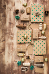 Top view of brown present boxes with sparkling embossed fur trees, pine cones, golden baubles, wooden decorations, jute twine, copy space for text