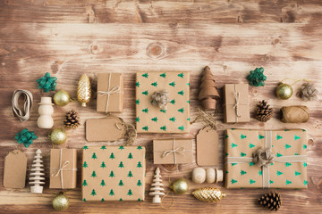 Christmas arrangement, brown present boxes with sparkling embossed fur trees, pine cones, golden baubles, wooden decorations, jute twine, top view, copy space for text