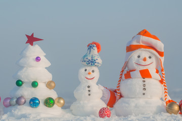 Snowmen with smiley faces in hats on winter day