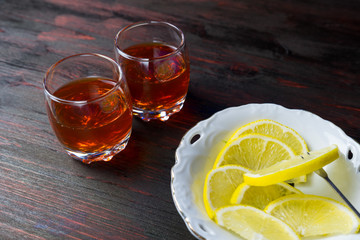 A glass of alcohol and sliced lemon.