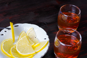 A glass of alcohol and sliced lemon.