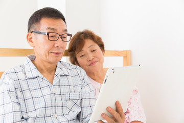 シニア夫婦　タブレットコンピューター　ベッド