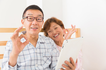 シニア夫婦　タブレットコンピューター　ベッド