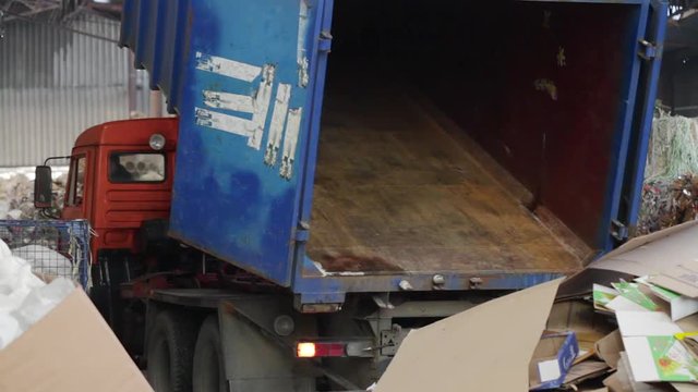Garbage truck unloads the waste paper at the garbage recycling plant. Close-up shot. Material Recovery Facility. Sorted cardboard waste ready for reprocessing.