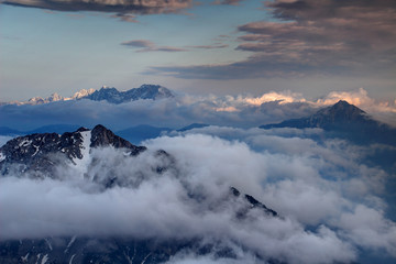Obraz premium Sharp peaks of Karavanke range and Kamnik Savinja Alps rise above evening fog and clouds, Begunjscica Veliki vrh, Storzic, Grintovec, Jezerska Kocna and Skuta peaks, Carniola Gorenjska Slovenia Europe