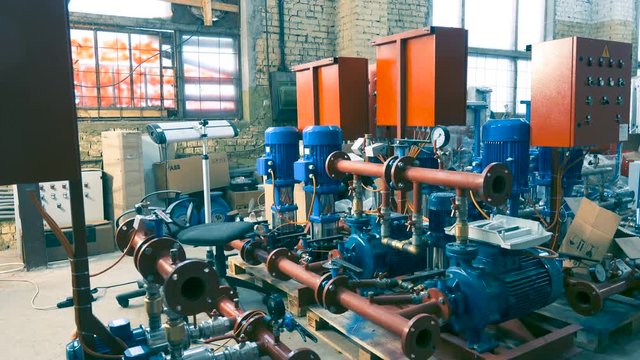  Dolly shot of a number of new water pumps before a large-scale assembly in a factory interior.