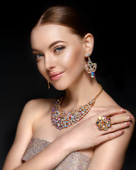 Model in set of jewellery. Luxury girl in shine jewelry from precious stones, diamonds. Beautiful woman in a necklace, earrings and big ring. Beauty and accessories.