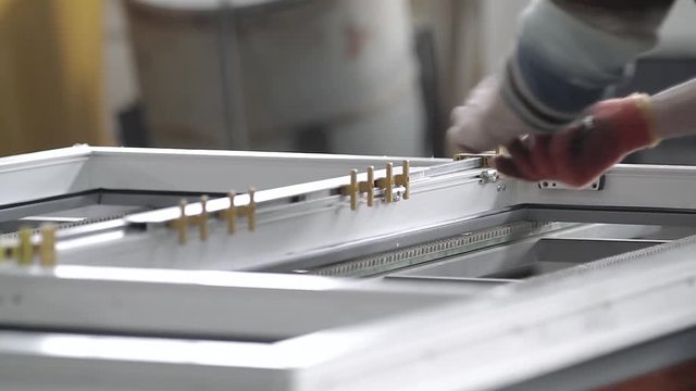 Worker install the fittings to plastic window. Manual worker assembling PVC doors and windows. Manufacturing jobs. Production of plastic windows.