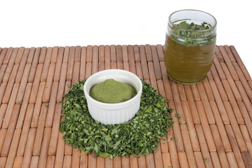 Moringa leaves with juice in a glass on wooden background