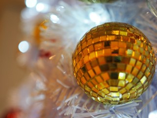 Golden ornament mirror ball on white Christmas tree. Have copy space for your text and blur white background.