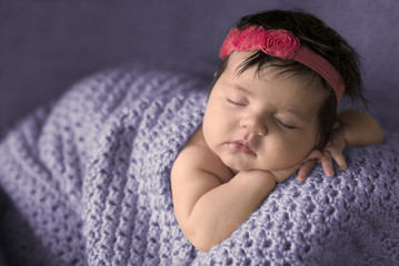 Sleeping infant girl wrapped in purple blanket