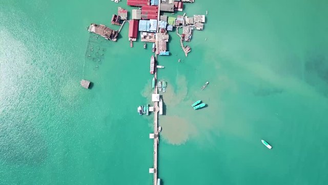 Drone aerial footage of Bang Bao fishing village, flying over traditional houses on piloti or stilt above sea water, with a pier in Koh Chang Thailand