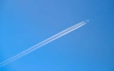 Large plane flying though blue sky with vapor trails