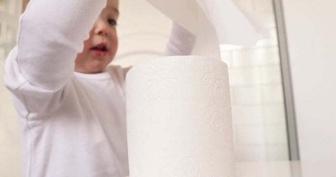 Toddler playing with toilet paper in the toilet close-up