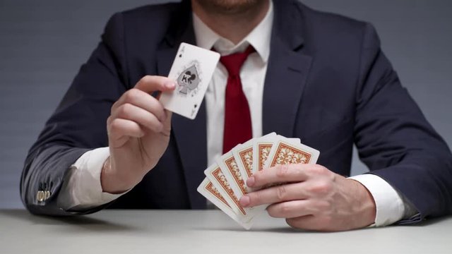 Man holding playing cards in hand and showing card ace. Gambling card game
