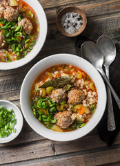 Multi grain, meatballs and vegetables soup  on a wooden rustic background, top view. Comfort home...