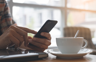 Man using smart phone in cafe and working on laptop computer