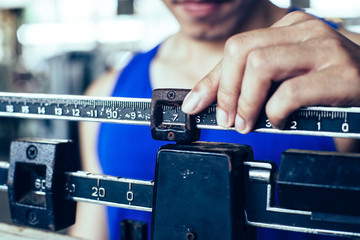 Sport man weighing himself on balance weight scale at the gym