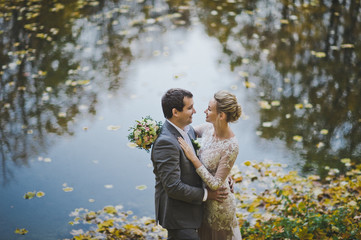 A dreamy portrait of the newlyweds on the shore of a forest lake in autu