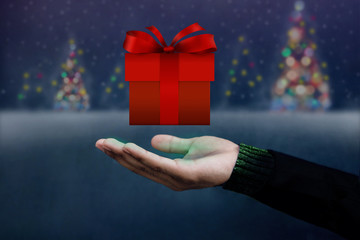 Christmas and New Year Concept, Hand opened to Present a Red Gift Box, Float like a Magic, Blurred Snow and X'Mas Tree as Background