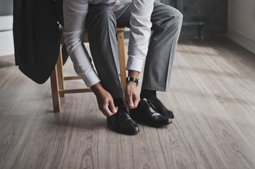 A man in a business suit ties the laces 336.