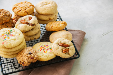 Set of festive cookies on a wire rack. Peanut butter, pecan, oatmeal, shortbread, snickerdoodle round biscuits. White stone background with copy space.