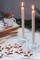 a cup of cocoa with marshmallow on a background of burning candles and cookies with icing - a festive concept, vertical photo
