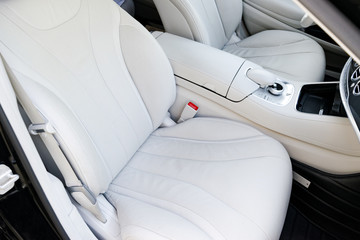 White perforated leather interior of the luxury modern car. Leather comfortable white seats and multimedia. Steering wheel and dashboard. automatic gear stick.