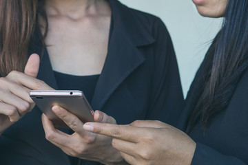 two business woman looking at mobile phone talking about their project while working together at office, technology with people concept
