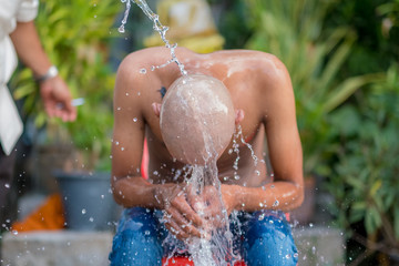 People take a shower after shave his head to become a monk in Thailand.- (Selective focus)