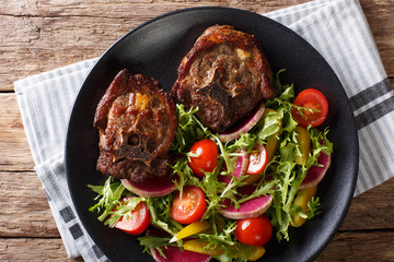 Spicy roasted lamb steak and radish salad, tomato and lettuce close-up. horizontal top view