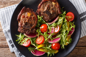 Spicy delicious lamb steak and salad from radish, tomatoes, pepper and lettuce close-up. horizontal top view