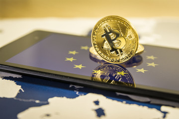 Financial concept with golden Bitcoin over smartphone, EU flag and map.