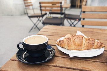 Breakfast, cups of coffee and fresh croissant on a table in a coffee shop