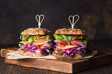 Two sandwiches with smoked fluke, red cabbage, rocca salad, red onion and red pepper on wooden...