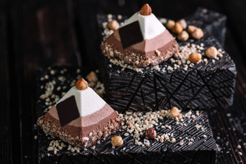 wo cakes three chocolate mousse in the shape of a pyramid on wood background