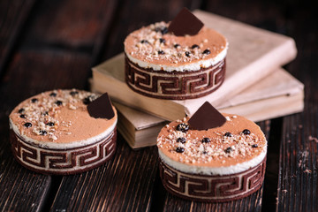Three original cakes decorated with chocolate and books on wood background