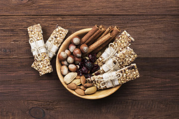 Cereal bars with nuts, berries and cinnamon on a wooden background. Top view. Food background