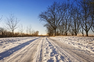Obraz premium Snowy winter road against sunset sky