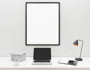 Workplace with blank laptop and frame