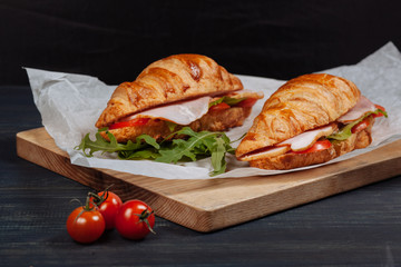 Fresh croissants with ham and tomatoes lying on the table