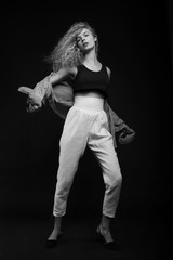 Full-length monochrome portrait of young woman posing over black background. Fashion studio shot.
